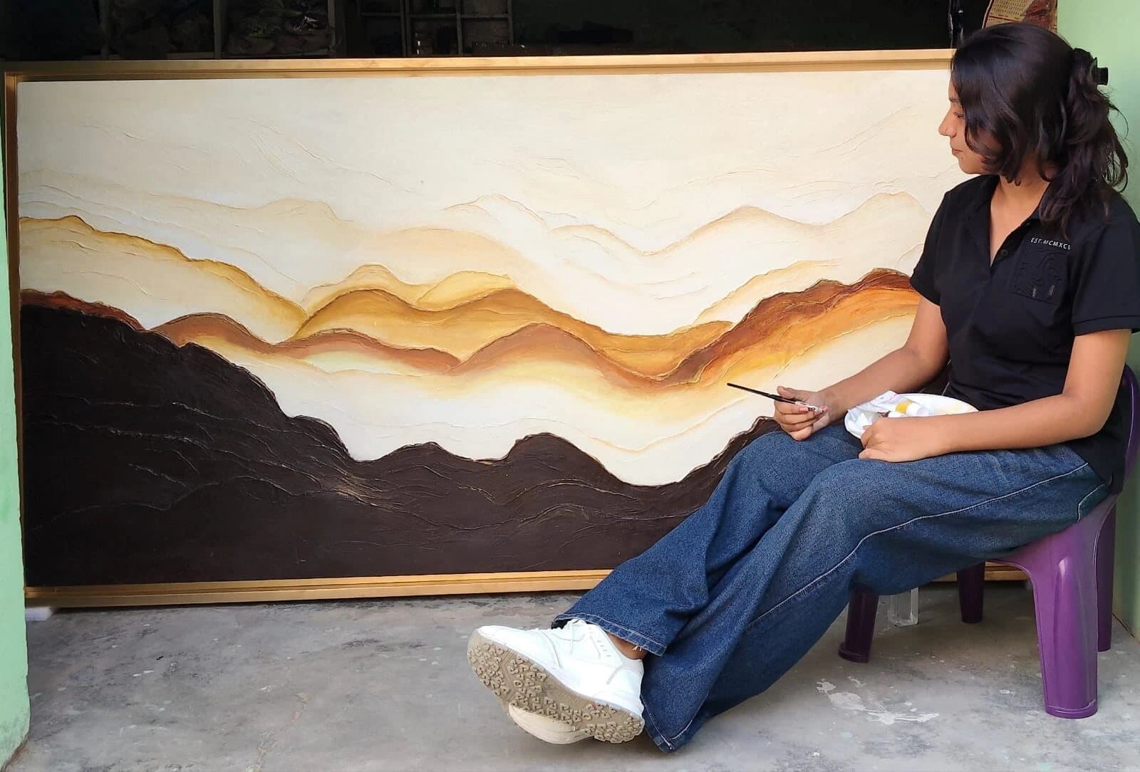 Bhawana seated beside “Textured Stone Layers”, a 6 ft hand-sculpted commission in earthy neutrals with gold detailing, before packing